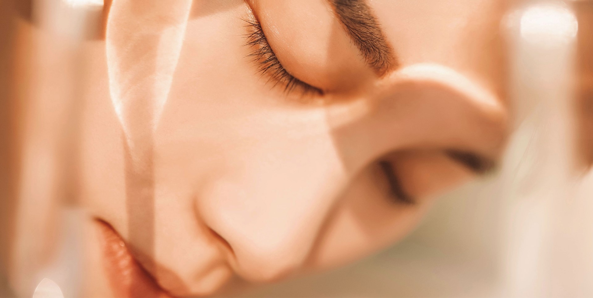 soft-focus close-up of a young woman's face with closed eyes, glowing skin and peaceful expression