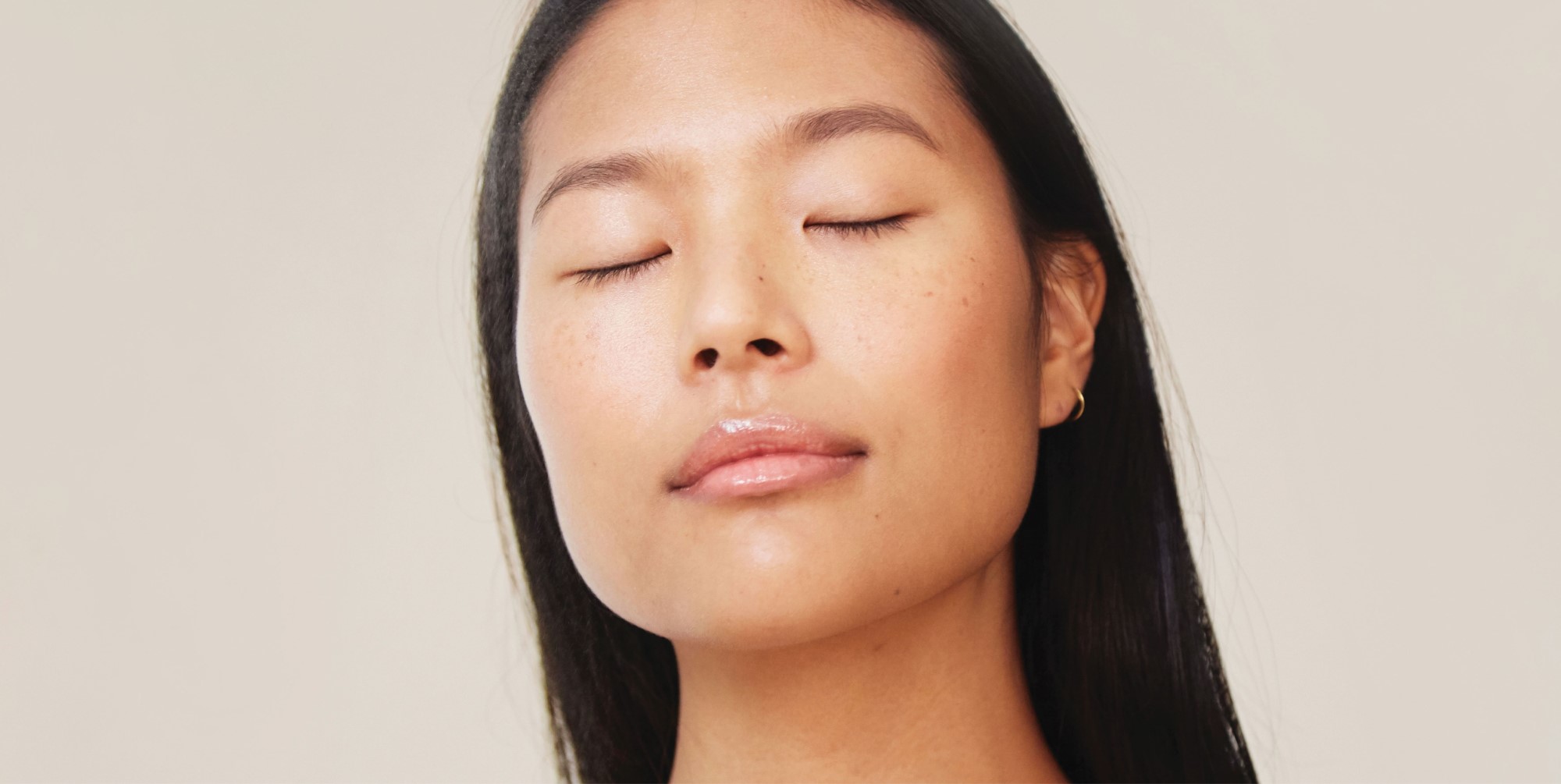 a young Asian woman with closed eyes, a serene expression, minimum makeup and small earrings, conveying a sense of softness