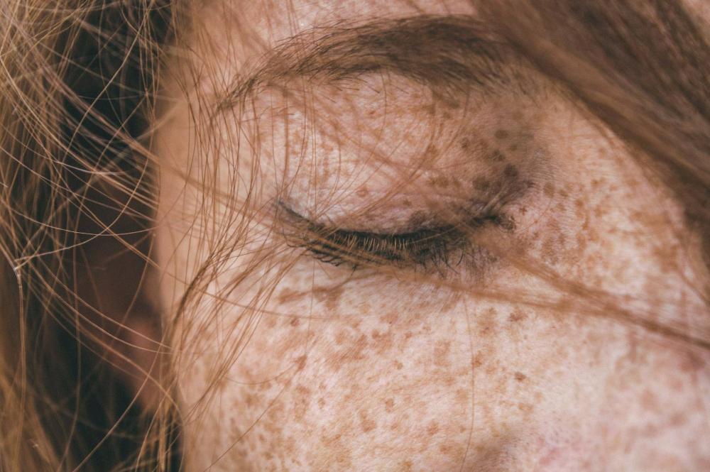 zoomed in girl's face with closed eyes, freckles and flowing red hair
