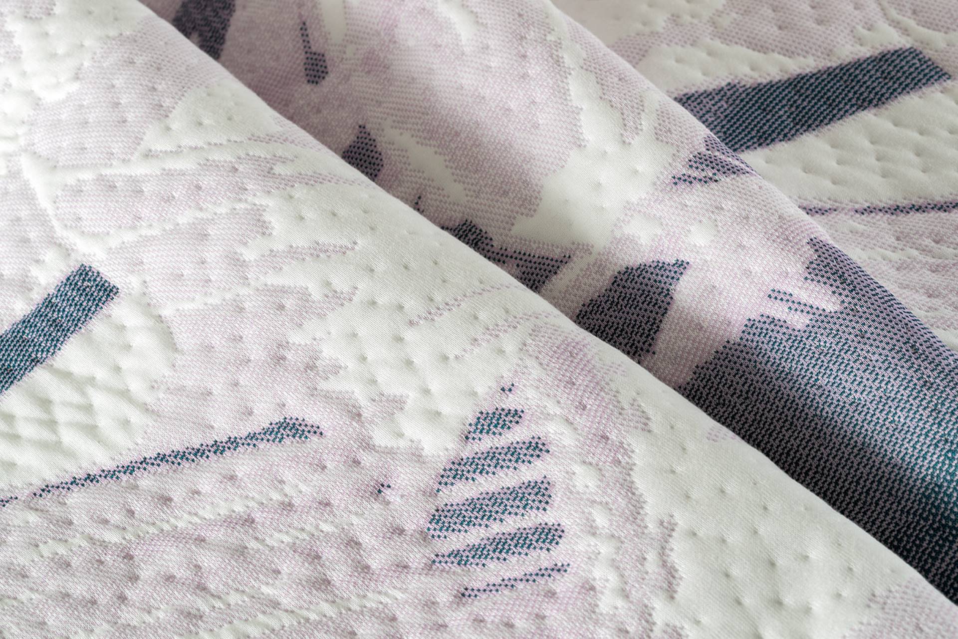 Gros plan d’un textile de matelas de qualité dans un mélange de blanc, violet et rose. 